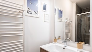 A bathroom with a white sink, wooden cabinet, and a towel rack.
