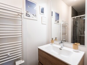 A bathroom with a white sink, wooden cabinet, and a towel rack.