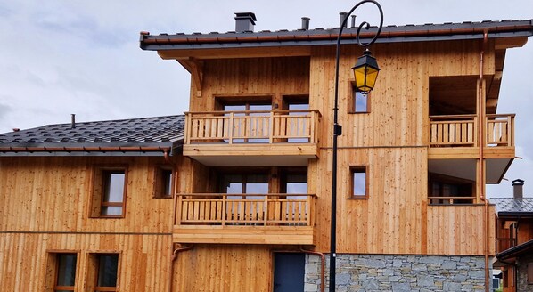 Een meerhoog gebouw van hout met balkons en een stenen fundering.