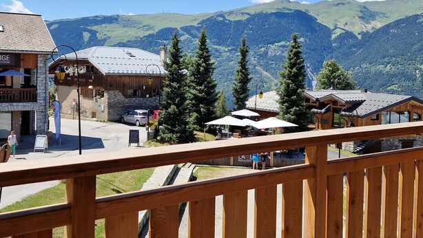 A mountain town with wooden buildings, a restaurant, and a view of green hills and mountains. - Beautiful apartment in Plagne Montalbert, near slopes with wifi and parking (La Plagne Montalbert)