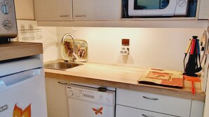 Een kleine keuken met een magnetron, een spoelbak en een vaatwasser.