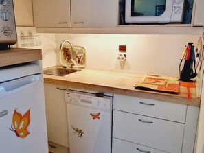 Cozinha compacta com micro-ondas, pia e máquina de lavar louça.