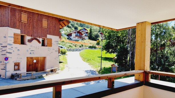 A balcony with a view of a traditional building and a pathway leading to a house in a green landscape. - Cozy 2-room apartment in Plagne Montalbert, close to slopes and shops, with garage and wifi (La Plagne Montalbert)