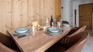 A dining table set with plates, glasses, a bottle, and a cheese block. - Cozy 2-room apartment in Plagne Montalbert, close to slopes and shops, with garage and wifi (La Plagne Montalbert)