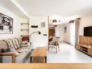 A modern living room with a sofa, a wooden coffee table, and a dining area with chairs and a table.