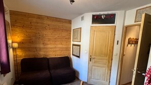 Ein gemütliches Zimmer mit einer Holzvertäfelung, einem dunkelbraunen Sofa, einem Holzesstisch und einer Tür mit herzförmiger Dekoration darüber.