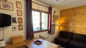 Ein gemütliches Zimmer mit Holztisch, einer Couch und einem an der Wand befestigten Fernseher.
