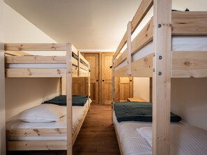 A bunk bed room with wooden walls and floors, a door, and a window.