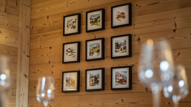 Een houten wand met ingelijste foto's van mooie landschappen.