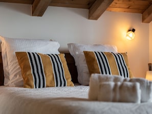 Een net opgemaakt bed met witte kussens en kussens met goud- en zwartgestreepte accenten.