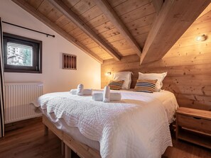 Een gezellige houten kamer met een bed, een raam en een radiator.