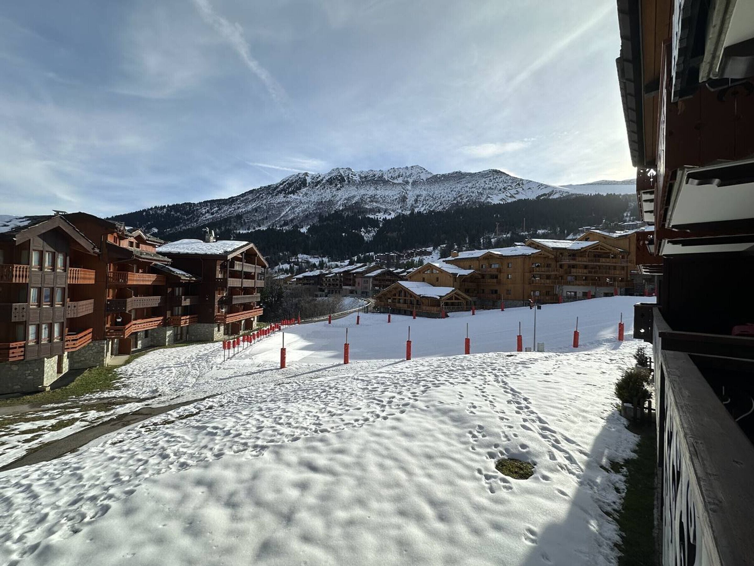A snow-covered ski resort with wooden buildings and a mountain in the background.