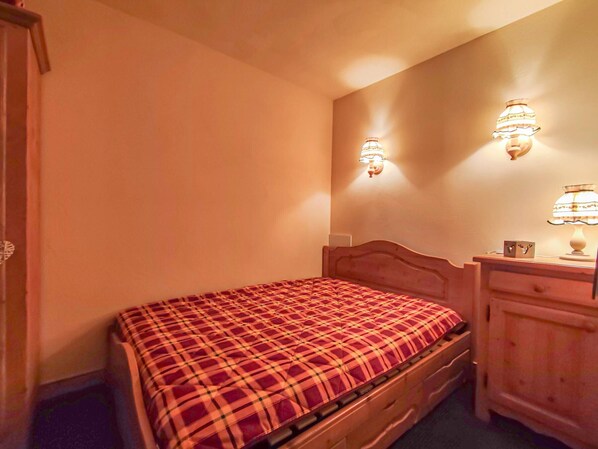A bedroom with a wooden bed, a nightstand, and two wall-mounted lamps.