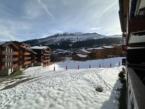 A snow-covered ski resort with wooden buildings and a mountain in the background.