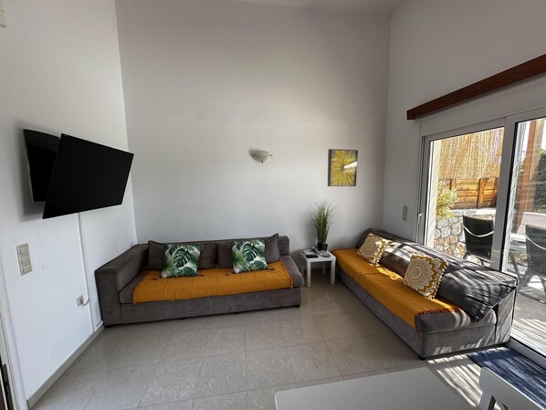 A modern living room with a grey sofa, a yellow ottoman, and a small side table with a plant.