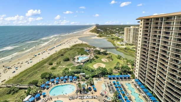 Un resort con una amplia zona de piscina, acceso a la playa y vistas al océano.