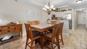 A spacious kitchen with white cabinets, a central island, and a chandelier. - Sandy Toes Paradise Retreat: 2BR Oceanfront Condo (North Myrtle Beach)