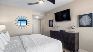 A bedroom with a bed, a dresser, a TV, and a mirror.