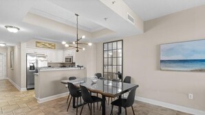 A modern kitchen with a central island, stainless steel appliances, and a dining area with a glass table and chairs.