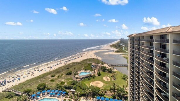 A beachfront hotel with a swimming pool, beach access, and a view of the ocean.