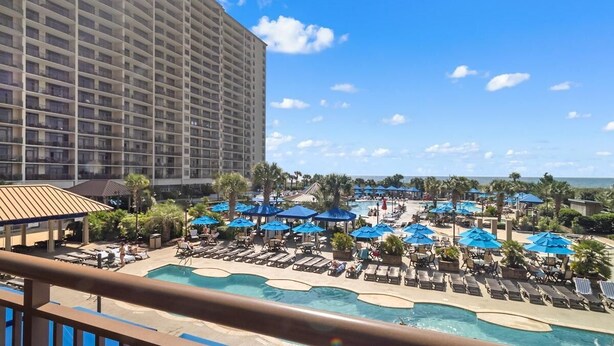 Um hotel com uma grande área de piscina, espreguiçadeiras e guarda-sóis.