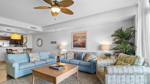 A modern living room with a blue sofa set, a wooden coffee table, and a patterned armchair. - Coastal Hideaway: 3 Bdrm Oceanfront Condo 3rd Flr (North Myrtle Beach)