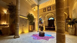 A spacious courtyard with a patterned floor, large columns, and a central fountain. - RIAD MALAÏKA (Essaouira)