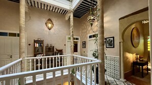 A spacious interior with a balcony, a staircase, and a patterned floor. - RIAD MALAÏKA (Essaouira)