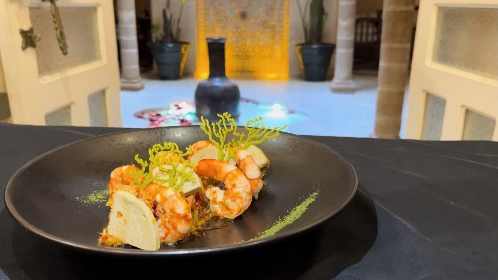 Un plato de comida con camarones y verduras sobre un plato negro.