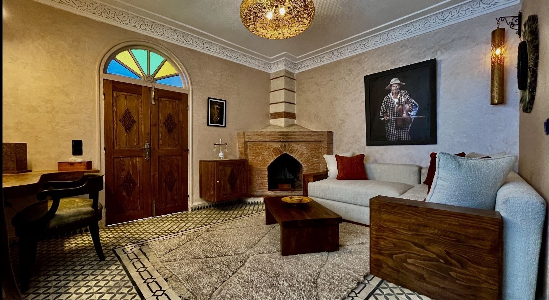Un salón acogedor con chimenea, un sofá, una mesa de centro de madera y una alfombra estampada.