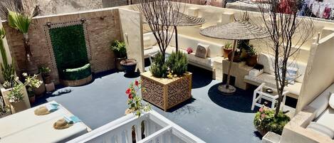 Eine Dachterrasse mit Pool, Sitzgelegenheiten im Freien und Topfpflanzen.