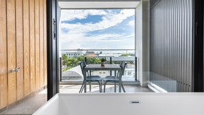 A modern bathroom with a bathtub, wooden cabinets, and a balcony with a table and chairs. - Ning Xia Time Villa (Dongshan)