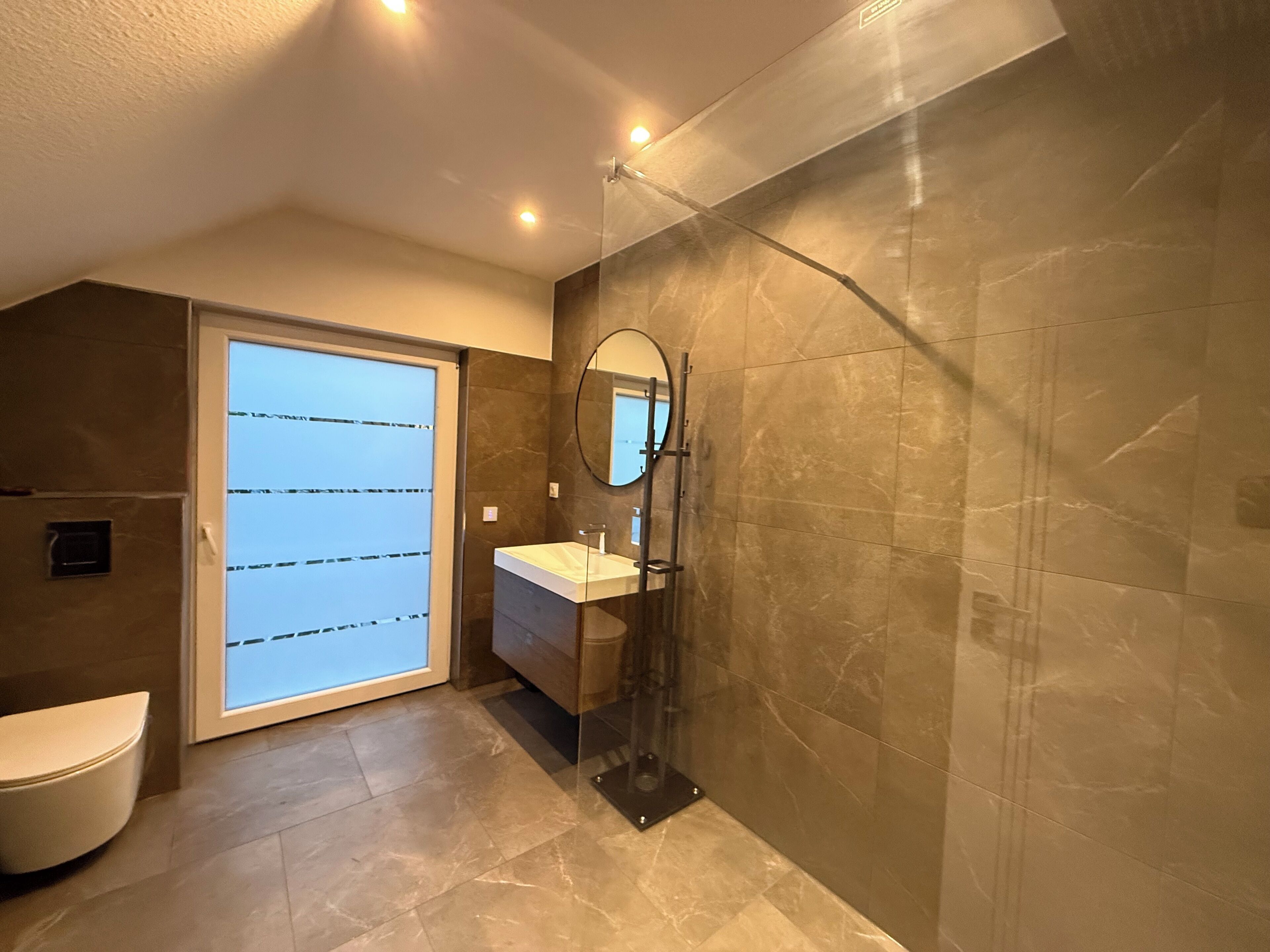 A modern bathroom with a glass shower enclosure, a sink, and a toilet.