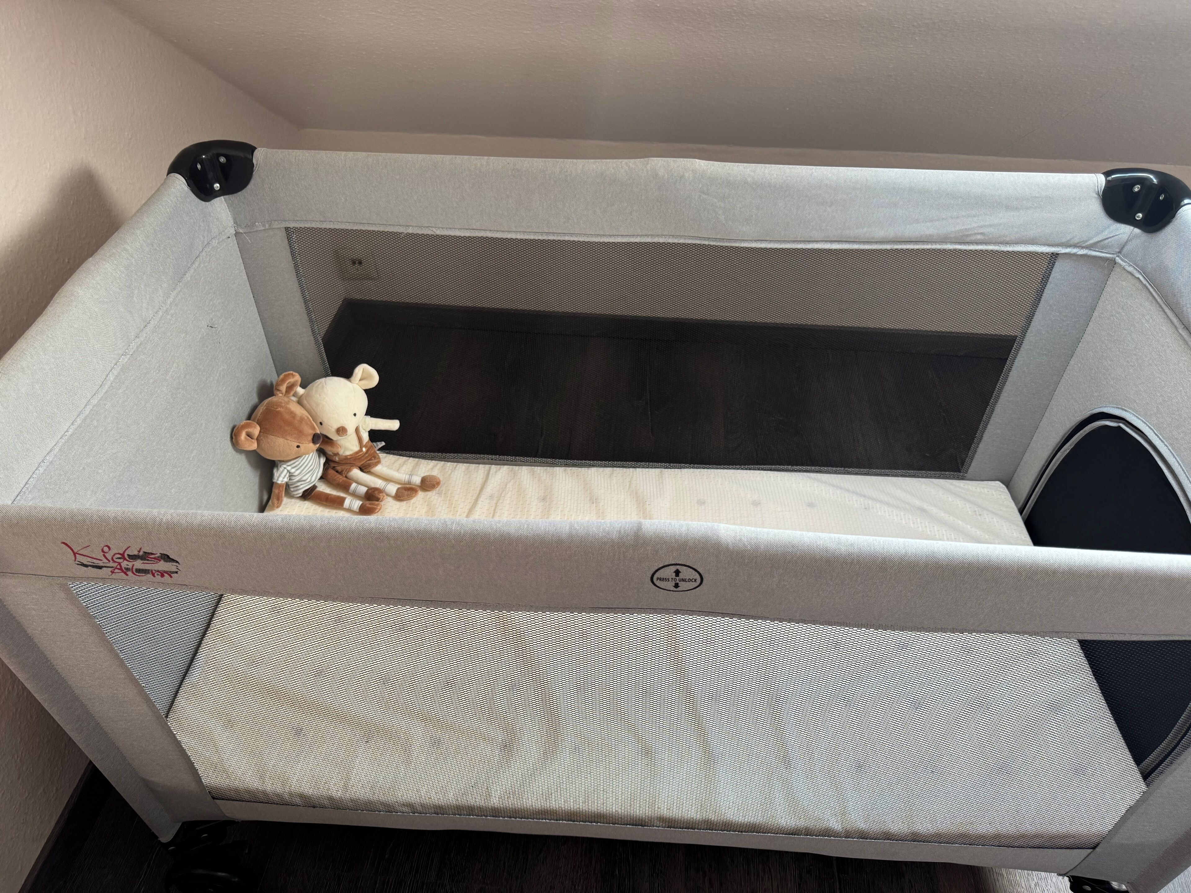 A baby crib with a mesh side and a soft mattress.