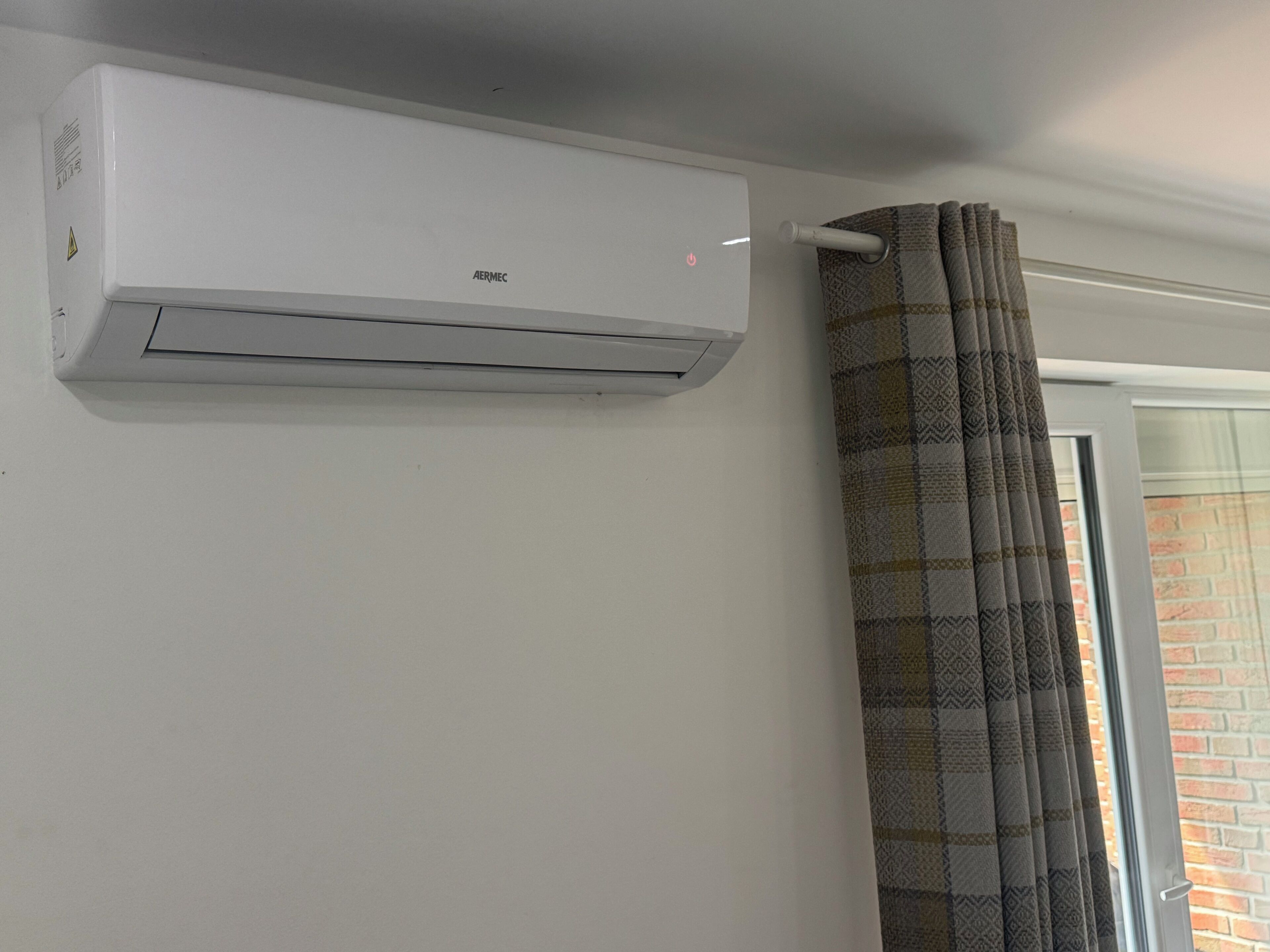Eine weiße AERMEC-Klimaanlage an der Wand montiert.