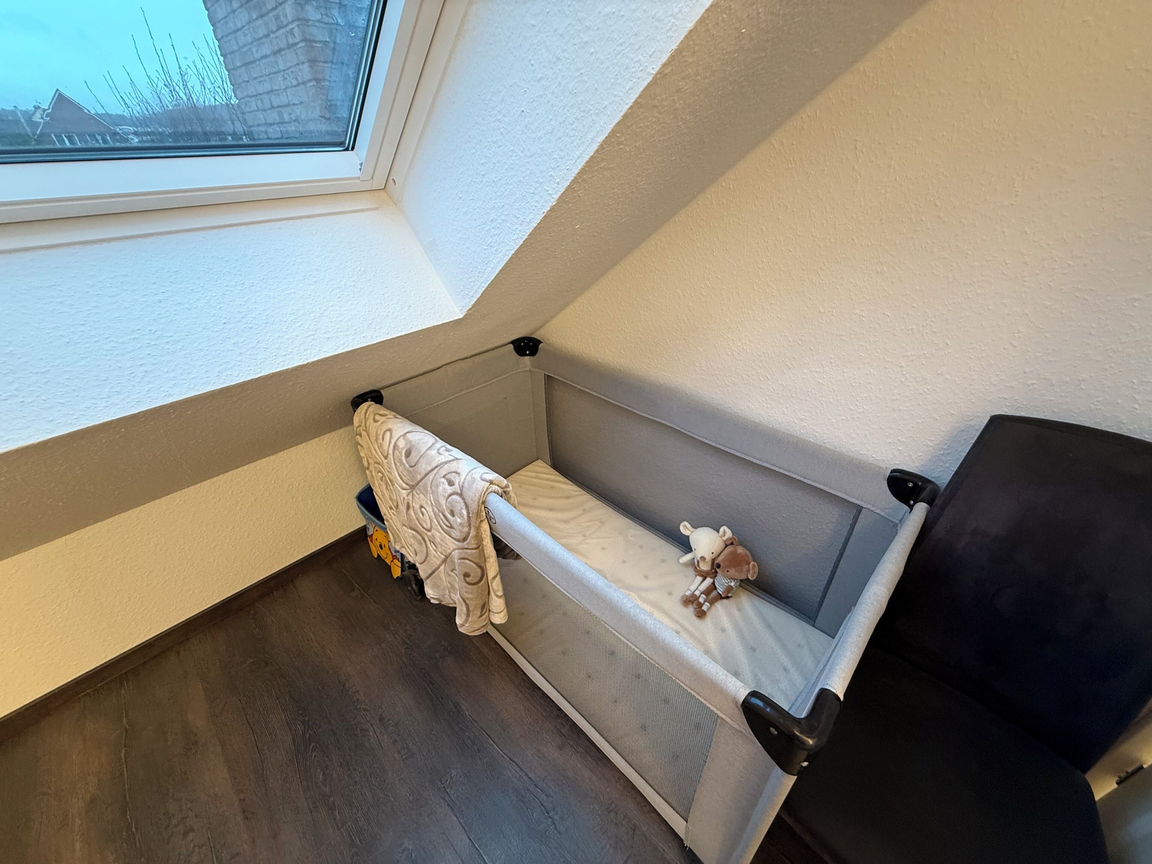Un petit espace clos aménagé pour dormir, avec une fenêtre, un banc et un coussin.