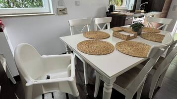 A dining area with a white table, woven placemats, and white chairs.