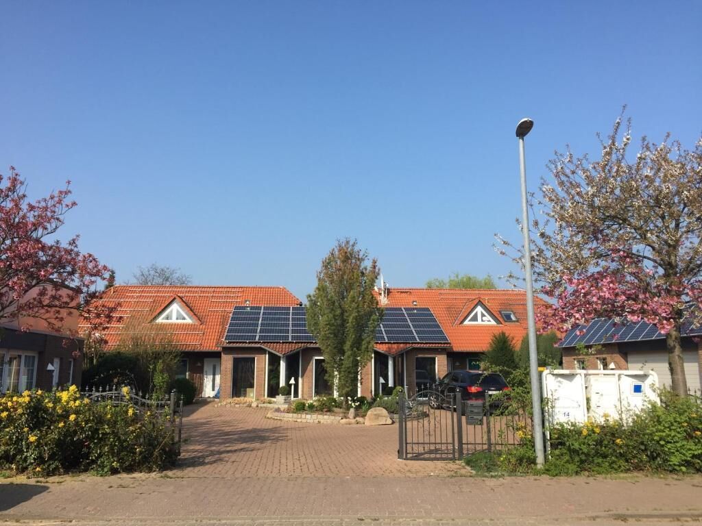 A residential area with houses featuring red-tiled roofs and solar panels.