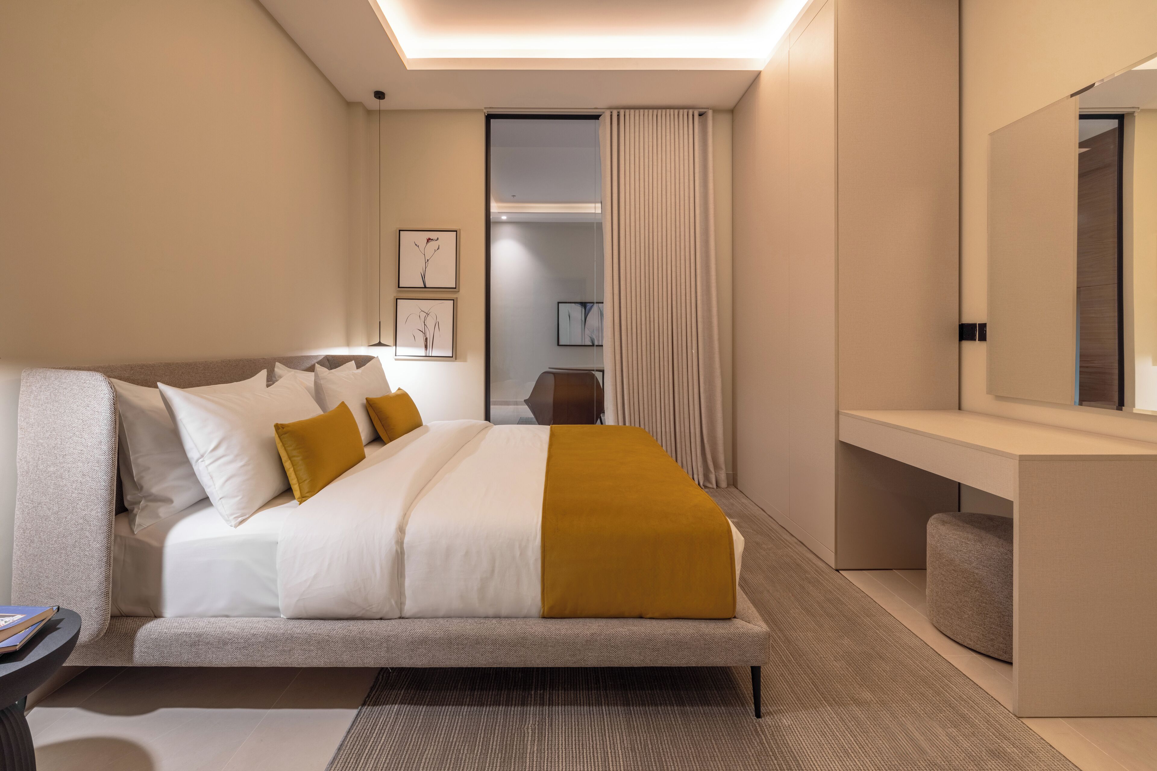 A modern hotel room with a large bed, a bedside table, a mirror, and a view of the hallway.