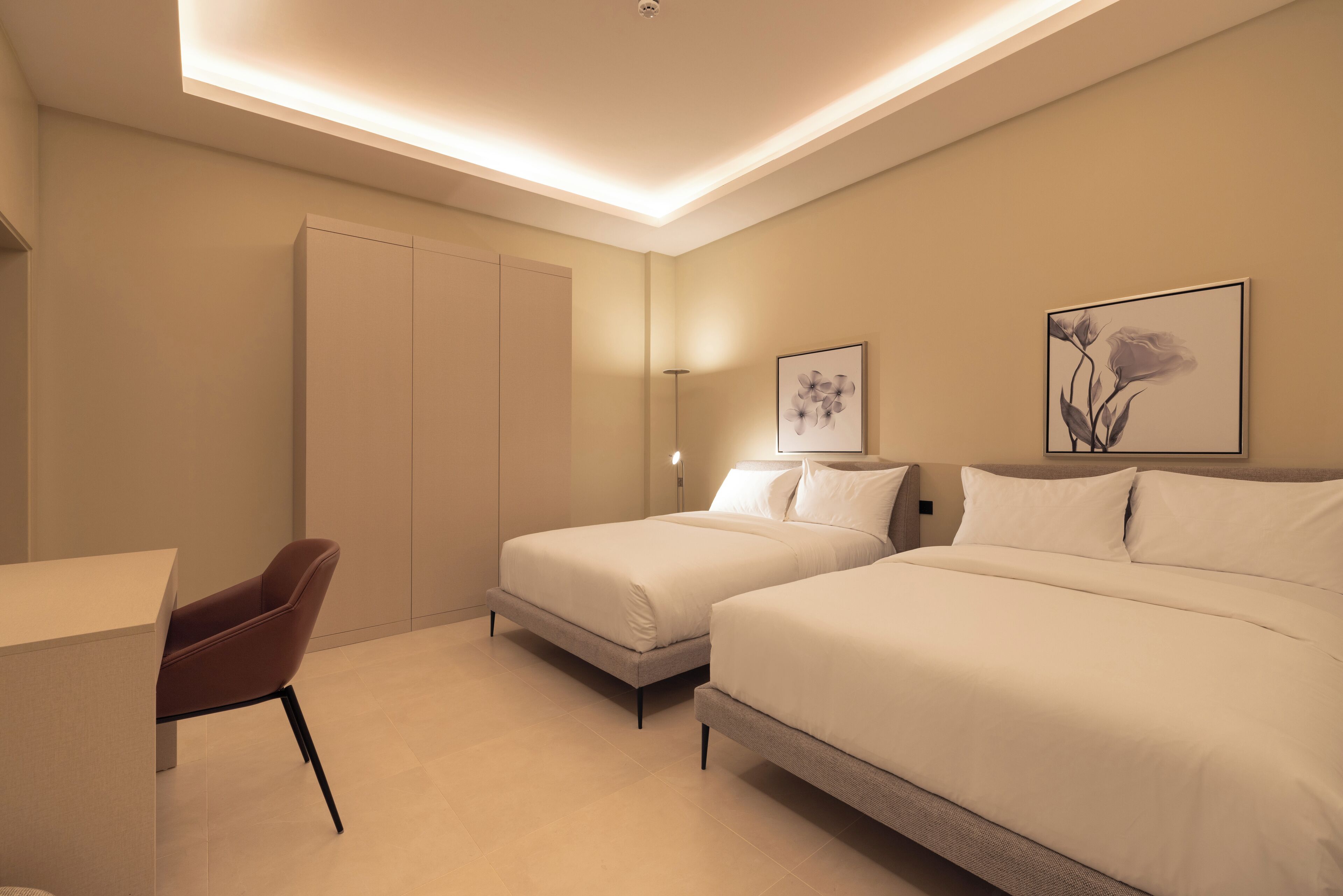 Une chambre d’hôtel moderne avec deux lits, un bureau et une chaise.