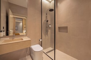 Une salle de bain moderne avec une douche à parois de verre, un lavabo avec un miroir et des toilettes.