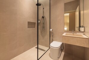 A modern bathroom with a glass-enclosed shower, a white toilet, and a sink with a mirror.