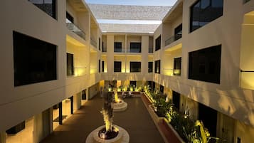 Um edifício moderno com um pátio central, várias varandas e um deck de madeira com jardineiras.