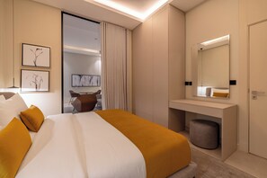 Une chambre d’hôtel moderne avec un grand lit, une table de chevet, un miroir et un petit coin salon.