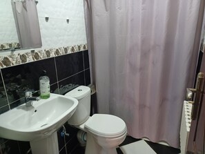 A bathroom with a white sink, toilet, and a shower curtain. - The Orchard Apartments: Simply Cozy, Peaceful & Clean Apartment Only 350 MAD!    (Ifrane)