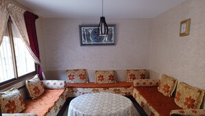 A room with a sofa set, a round table, and a decorative wall piece.