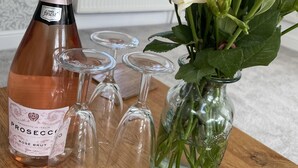 A bottle of rosé wine, several wine glasses, and a vase with pink and white flowers on a wooden table. - Barn Retreat/ Hottub/ Bbq/ Petsok/wi-fi (Evesham)