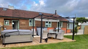 A backyard with a patio, outdoor furniture, and a dog. - Barn Retreat/ Hottub/ Bbq/ Petsok/wi-fi (Evesham)