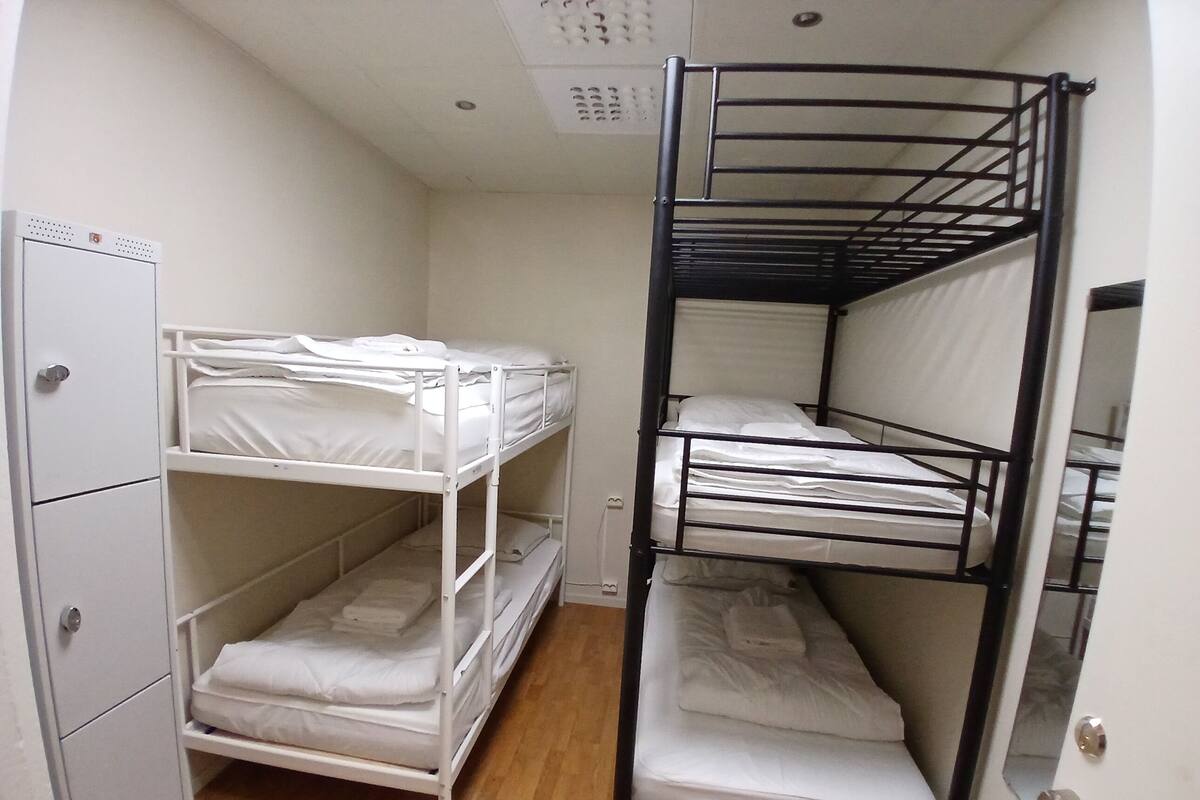 Une chambre avec un lit superposé, une armoire blanche et une porte.