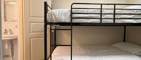 A bunk bed room with a white door, a small sink, and a ceiling light.